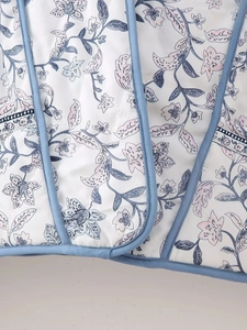 Detailed macro view of diamond quilted floral fabric with blue decorative piping