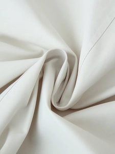 Close-up of beige twill fabric texture and precise stitching on short trench coat