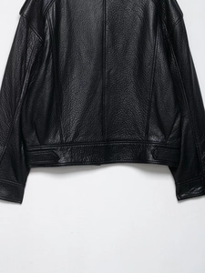 Détails de l'ourlet d'une veste en cuir noir avec texture grainée et sangles de réglage