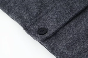 Détail du tissu en laine mélangée gris foncé avec un bouton classique en résine noire