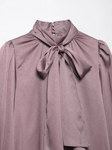 Gros plan sur une chemise en satin rose avec col à nœud élégant et texture soie fine
