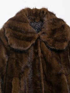 Detail of faux fur coat collar with inner lining texture and brand label