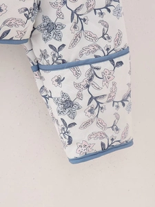 Detailed close-up of diamond quilted sleeve with floral patterns and navy blue piping
