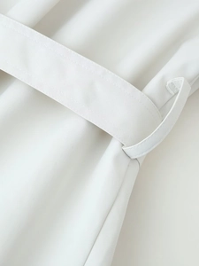 Detailed close-up of a cream cropped trench coat featuring a matching fabric belt and loops