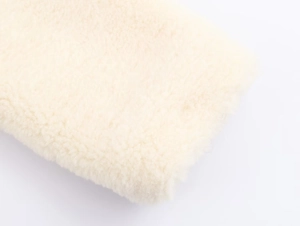 Detailed close-up of cream faux fur fabric texture showing soft curly plush fibers
