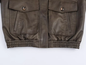 Close-up of deep brown vintage faux leather jacket with elastic waist and button pockets