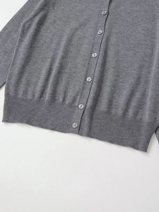 Detail einer grauen Strickjacke mit marmorierten Knöpfen und Rippenstrick-Abschluss