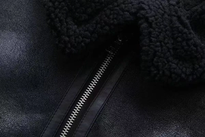 Close-up of black faux leather jacket with metal zipper and soft fleece shearling collar
