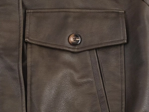 Close-up of brown suede jacket pocket with flap design and tortoiseshell button detail