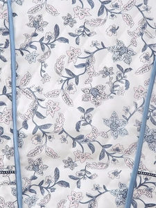 Close-up of floral quilted jacket fabric with detailed stitching and blue vine patterns