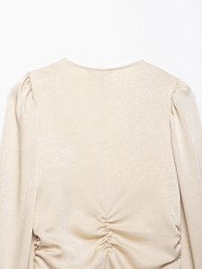 Detail of beige satin shirt featuring elegant puff sleeves and gathered ruched texture