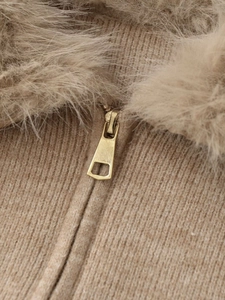 Detail view of knitted faux fur jacket with golden metal zipper and ribbed texture