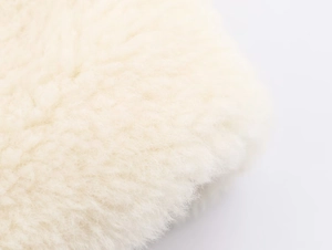 Macro view of creamy faux fur texture showing soft fluffy fibers of the belted coat