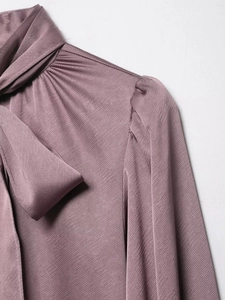 Gros plan détaillé d'un chemisier en satin violet avec col à nouer et épaules plissées