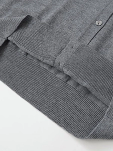 Detail der grauen Strickjacke mit geripptem Saum und passendem Knopfverschluss