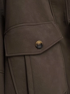 Detail shot of a dark brown faux leather jacket featuring a large flap pocket and marble button