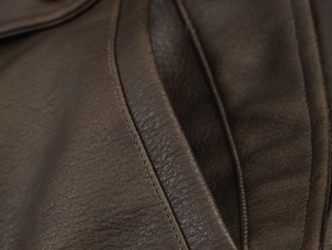 Detailed macro view of dark brown faux suede jacket with professional double stitching