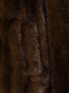 Macro shot of dark brown faux fur jacket showing rich fiber texture and high quality