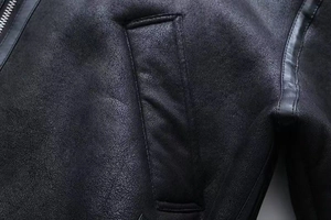 Detail of black faux suede jacket texture with silver zipper and leather piping