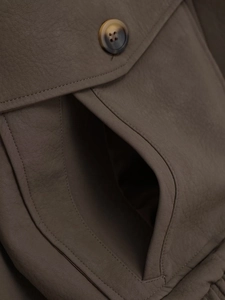 Detailed macro view of taupe faux leather jacket with flap pocket and textured button