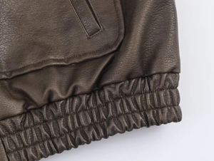Detail of dark brown pebble grain leather jacket with elastic hem and reinforced stitching