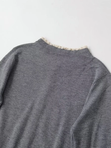 Detailaufnahme des grauen Strickoberteils mit feiner cremefarbener Spitze am Ausschnitt