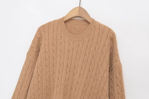Detail of camel chunky cable knit sweater with round neck hanging on wooden hanger