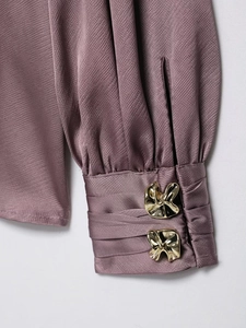 Détail de manche de chemise en satin avec poignets plissés et boutons dorés