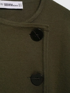 Dettaglio del cardigan in maglia verde scuro con trama a rilievo e bottoni in resina