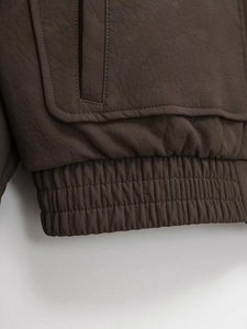Detailed view of the elastic ribbed hem and stitching on a dark brown leather jacket