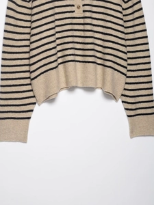 Detail of striped knit sweater showing beige and black pattern with buttoned neckline