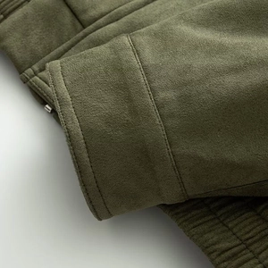 Detalle de la manga y el dobladillo de chaqueta de ante verde oliva con doble costura
