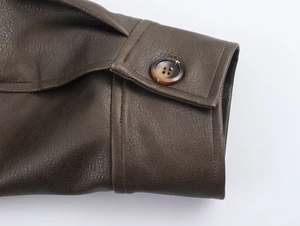 Detail of brown faux suede jacket cuff with stitching and marble texture button