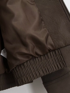 Macro detail of dark brown leather jacket featuring silky lining and elasticated hemline