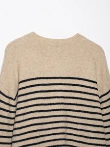 Close-up of beige knitted sweater showing soft wool texture and black horizontal stripes