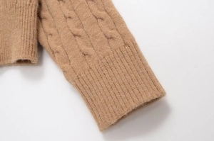 Close-up of warm khaki cable-knit texture and ribbed cuffs on loose knit sweater