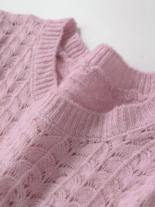 Gros plan du pull en maille rose avec motifs ajourés complexes et texture torsadée douce