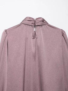 Détail du dos d'un chemisier en satin avec découpe en goutte et fermeture à bouton chic