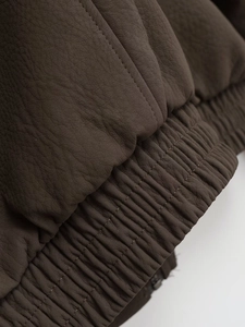 Detail of chocolate brown leather jacket with ribbed elastic hem and premium stitching
