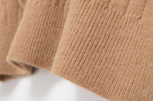 Close-up of brown cable knit sweater showing soft textured fabric and ribbed cuffs