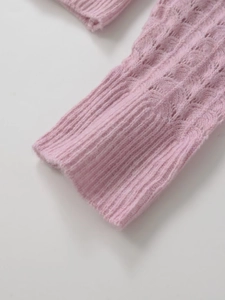 Détail de la manche d'un pull en maille torsadée rose avec poignets côtelés fins
