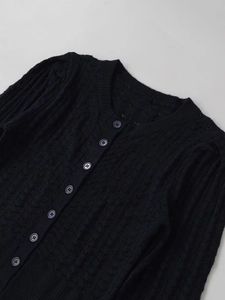 Detail of black pointelle knit cardigan featuring round neck and tonal button closure