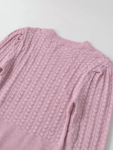 Vue macro du haut en maille rose avec texture ajourée ondulée et col rond côtelé