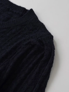 Close-up of the navy blue knit sweater featuring ribbed texture and round neckline details