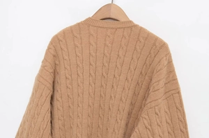Detailed macro view of the cable knit texture and oatmeal wool fabric of this sweater