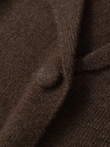 Close-up of a dark brown knit cardigan featuring a textured fabric and matching covered button