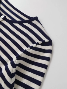 Détail du cardigan rayé bleu et blanc montrant le col rond et la texture du bouton blanc