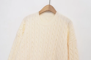 Close-up of cream white cable knit sweater featuring round neck and chunky texture