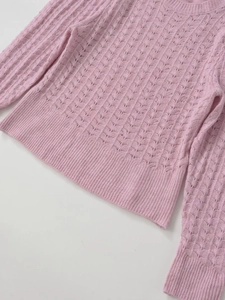 Vue détaillée du pull en maille rose avec des motifs ajourés ondulés délicats