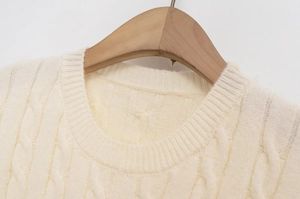 Close-up of cream cable knit sweater showing round ribbed neckline and thick texture